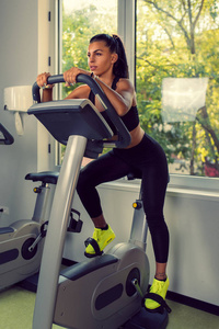 在健身房的固定自行车上做有氧运动的女人