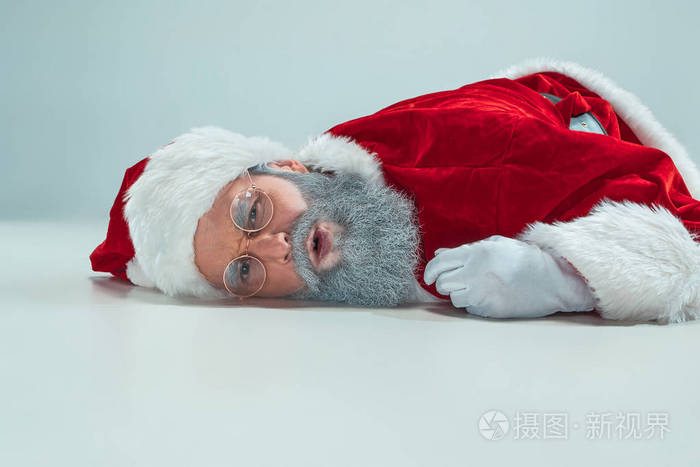 红色白色圣诞老人劳累过度的挫折倦怠概念躺在地板上孤立的白色背景