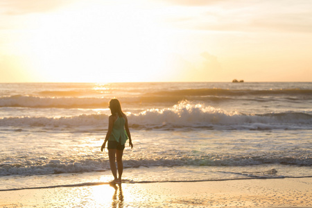 女人走在沙滩上，在早晨夏天海的阳光