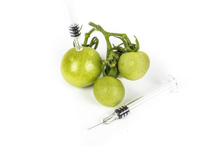 小的绿色西红柿葡萄用注射器。概念非有机食品, 基因改造有机体。白色背景。写作地点