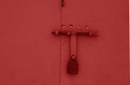 在金属门上的旧挂锁红色的颜色。抽象背景和纹理