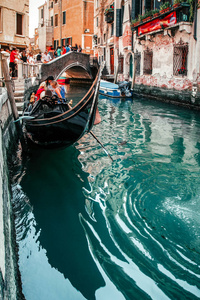 意大利威尼斯的船夫和游客在狭窄运河上的传统缆车