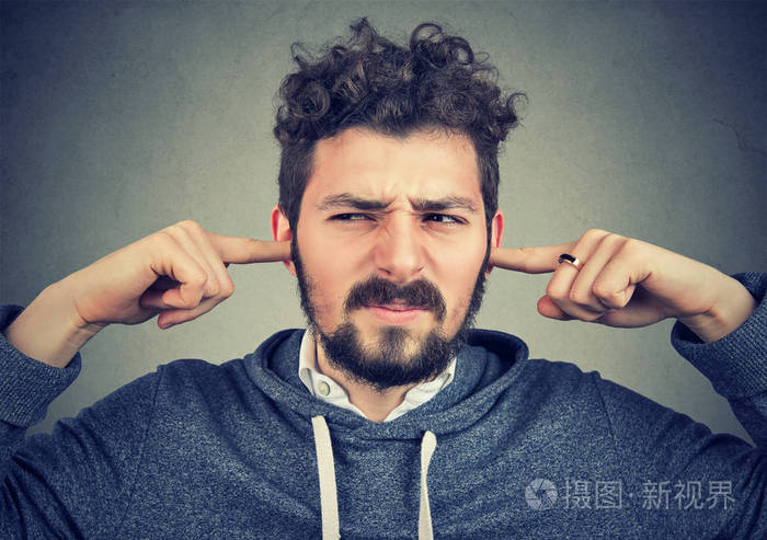 特写肖像的一个不愉快的人用手指堵住耳朵不想听孤立的灰色墙壁背景