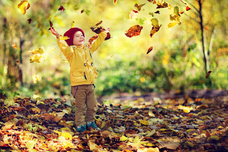 快乐小男孩投掷叶子在空气中