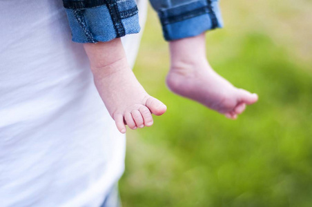 可爱的小脚丫, 一个新生的男婴女孩。父亲抱着一个婴儿在他手中的股票形象。第一个儿童概念。爱与关怀