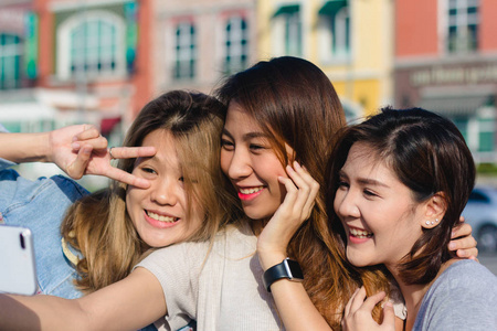 漂亮的亚洲朋友, 女人使用智能手机。快乐年轻的亚洲青少年在城市城市, 而与她的朋友一起与智能手机的自画像