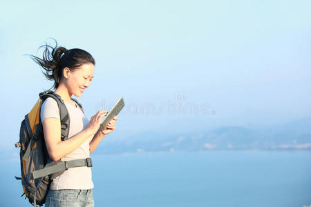 女徒步旅行者在海边使用平板电脑