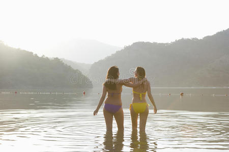 比基尼女子双臂环抱站在湖中