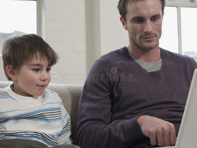 男孩和父亲在家里看笔记本电脑