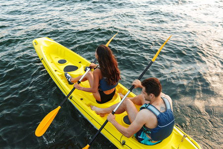 一对年轻夫妇在湖上划独木舟后视图