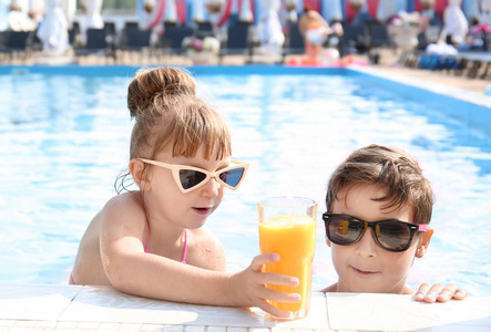 夏天的游泳池里, 可爱的孩子们带着杯果汁。