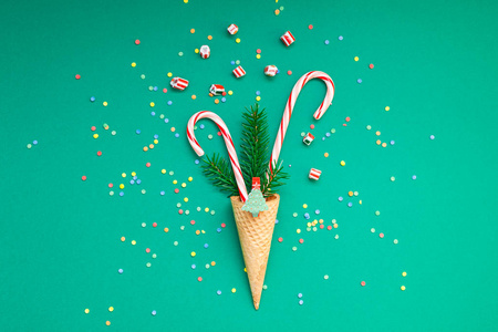 新年圣诞节圣诞佳节聚会庆祝华夫饼锥糖手杖冷杉树枝复制空间绿彩纸背景。模板贺卡2019