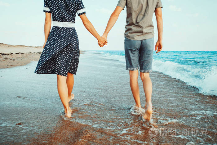年轻爱的情侣在岸上漫步海浪和牵手, 海滩夏季假期