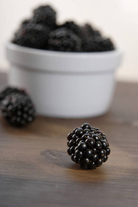 白色碗与新鲜成熟的黑莓在木质背景, 特写