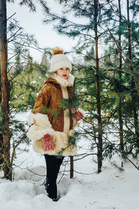 冬天的小女孩在一天中满是雪的森林里穿衣