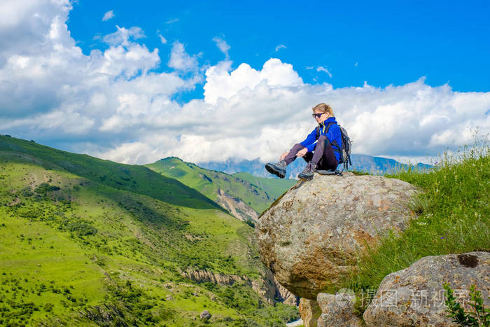 一个背着背包的女孩坐在一块石头上.山风景.在高加索爬山