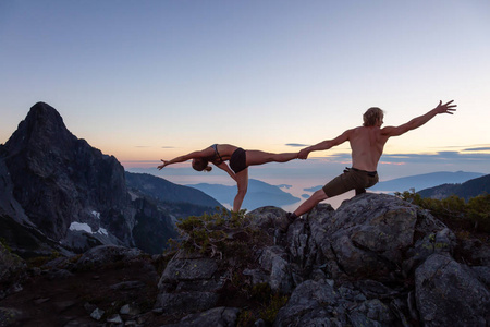 在一个充满活力的夏日日落中, 男人和女人在山上 acroyoga。在豪声中拍摄, 靠近温哥华, 加拿大不列颠哥伦比亚省