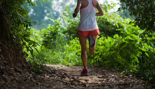 年轻女子小径赛跑者在热带森林小径上奔跑