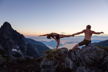 在一个充满活力的夏日日落中, 男人和女人在山上 acroyoga。在豪声中拍摄, 靠近温哥华, 加拿大不列颠哥伦比亚省