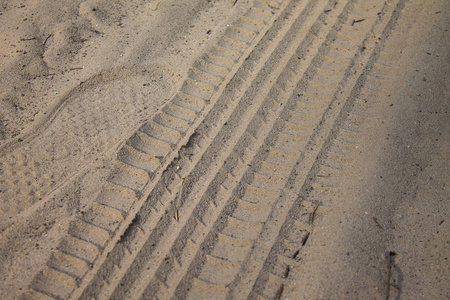 在沙子上的轮胎痕迹接近图像。有质感的轮胎痕迹在沙子特写。工业背景。车轮保护器带肋印记