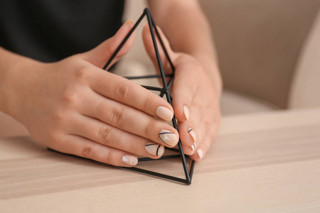 年轻女子与时尚的指甲持有装饰金字塔在桌子上, 特写