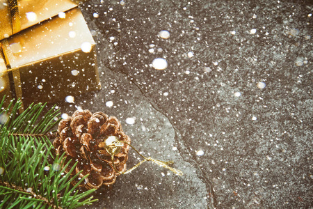 圣诞背景。金色礼品盒圣诞树枝和圆锥, 石板背景, 复制空间。雪效应