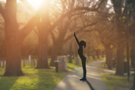 上练瑜伽的公共公园在日落时的剪影年轻女人