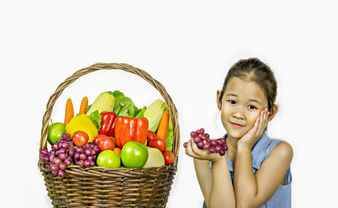 微笑亚洲小女孩与果子和蔬菜在篮子在白色背景下