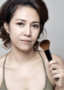 亚洲年轻美女应用化妆粉刷面部白色背景