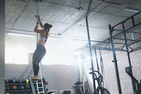 健身房训练。女性 Crossfit 运动员攀登绳索