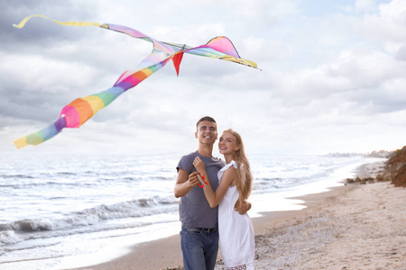 快乐的年轻夫妇在海上放飞风筝