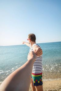 男友拉着她的女孩, 向大海海洋展示。焦点在手上