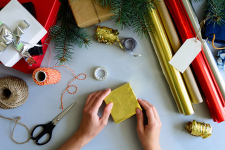 女人的手装饰现在的盒子上灰色的木质背景。新年和圣诞装饰品概念