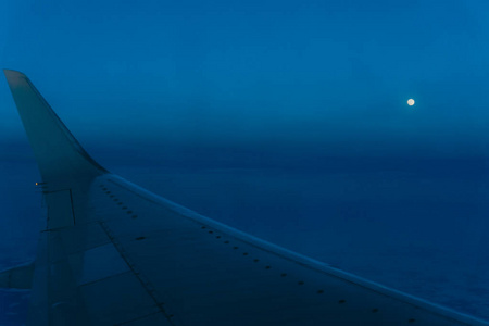 一架大型客机从舷窗的机翼在傍晚的飞行中, 在一个美丽的黑暗的天空背景