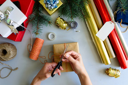 女人的手装饰现在的盒子上灰色的木质背景。新年和圣诞装饰品概念