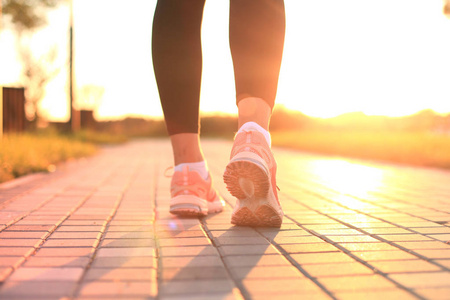 赛跑者脚跑在路特写在鞋子, 室外在日落或日出