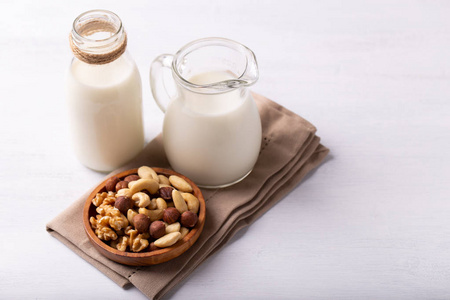 健康天然非牛奶在玻璃和碗坚果在白色木桌