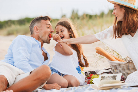 幸福的家庭与父亲, 母亲, 女儿在海滩野餐, 笑