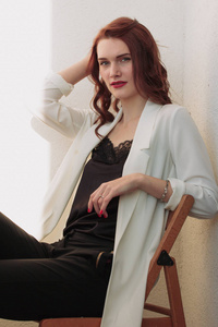 美丽的 redhear 女人白夹克, 高跟鞋, 和黑色衬衫坐在 balcone