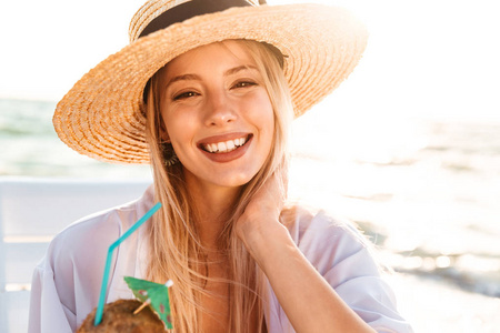 快乐的年轻女人的照片20s 夏季草帽在海边的日出欢笑和饮酒鸡尾酒