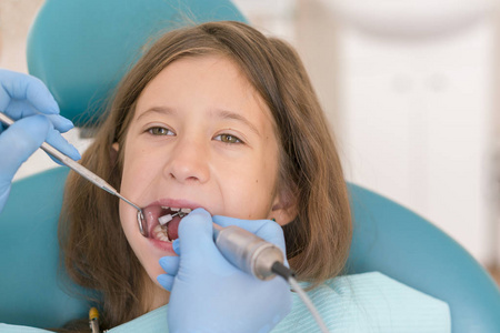 牙医的小女孩, 牙科治疗。在牙科医生的开放口的小孩子的宏观关闭。牙医办公室的牙齿检查。牙科医生检查牙医椅上的女孩牙齿