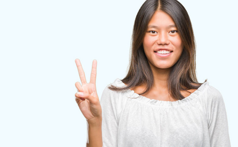年轻的亚洲妇女在孤立的背景显示和指向手指第二, 而微笑着自信和快乐