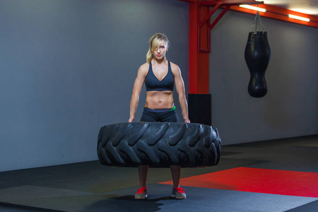 适合女运动员的工作与一个巨大的轮胎, 转动和携带在健身房。Crossfit 妇女运动与大轮胎