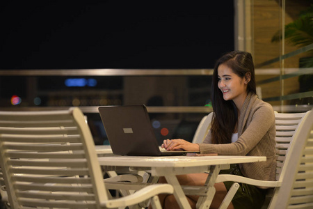 晚上在户外使用笔记本电脑的快乐女人