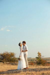 快乐的新婚夫妇与美丽的田野花束户外