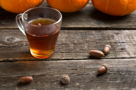 秋季背景为感恩节或万圣节的概念在一个木桌上南瓜, 一杯茶和橡子