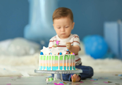 可爱的小男孩与生日蛋糕坐在地板在房间里