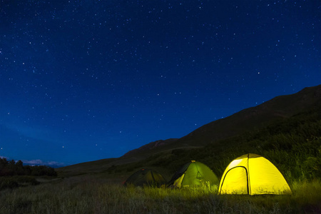 夜间露营。帐篷里的光。星光灿烂的天空。多天的旅行