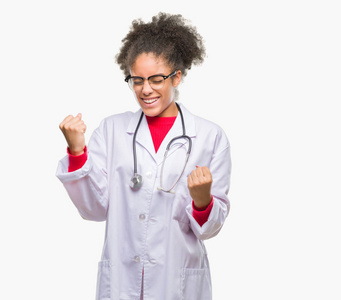 年轻的美国黑人医生在孤立的背景下非常高兴和兴奋做赢家手势与手臂举起, 微笑和尖叫的成功。庆祝概念