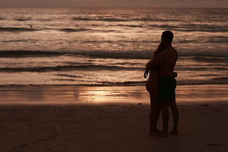 日落美景, 沙滩上的年轻快乐恋人剪影。新婚夫妇蜜月度假酒店